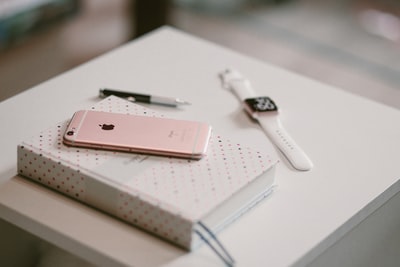 苹果手表旁的书上有玫瑰金iPhone 6s